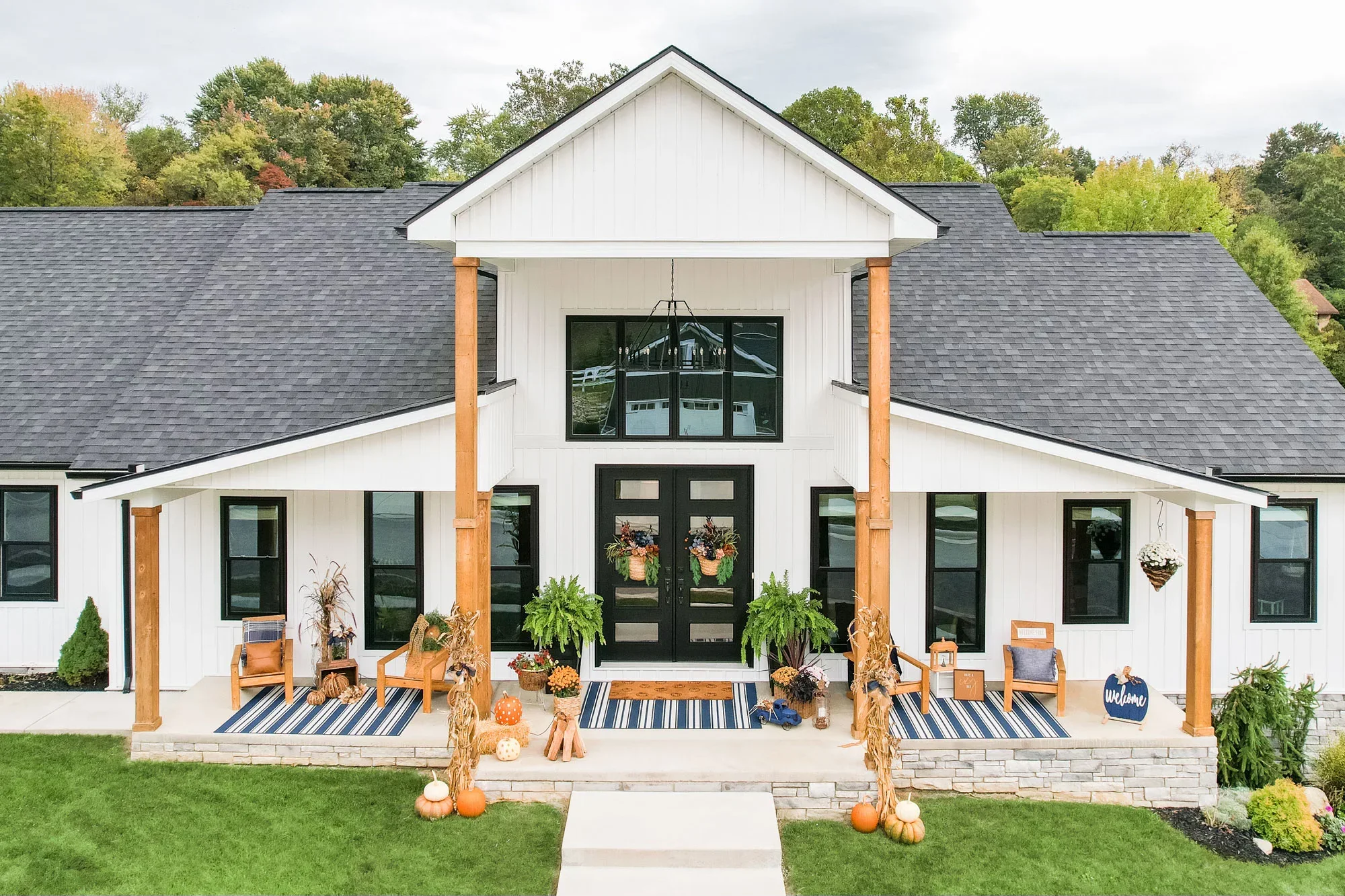 Charcoal gray asphalt shingle roof on white farmhouse with black windows and wood columns